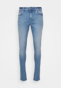 Jeans de denim azul claro con un ajuste tapered, cinco bolsillos, cierre de botón y una sutil textura desgastada en toda la tela.