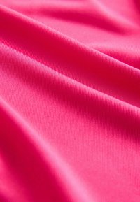 Helderroze stof met een gladde textuur en fijne ribbels. Het materiaal lijkt licht en flexibel te zijn en vangt het licht subtiel op.