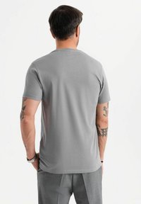T-shirt grigio a maniche corte realizzata in tessuto morbido, con colletto a girocollo standard e un design semplice senza loghi o fantasie visibili.