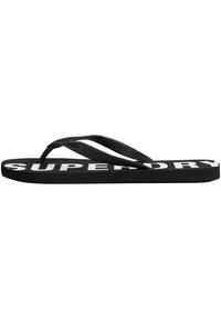 Tongs noires avec des brides en caoutchouc, dotées d'une semelle texturée et de "SUPERDRY" imprimé en blanc sur la semelle intérieure.