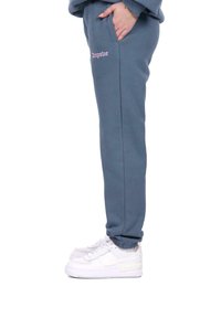 Blå sweatpants med en afslappet pasform, sidelommer og broderet "dropsize" tekst i pink. Sammen med hvide sneakers.