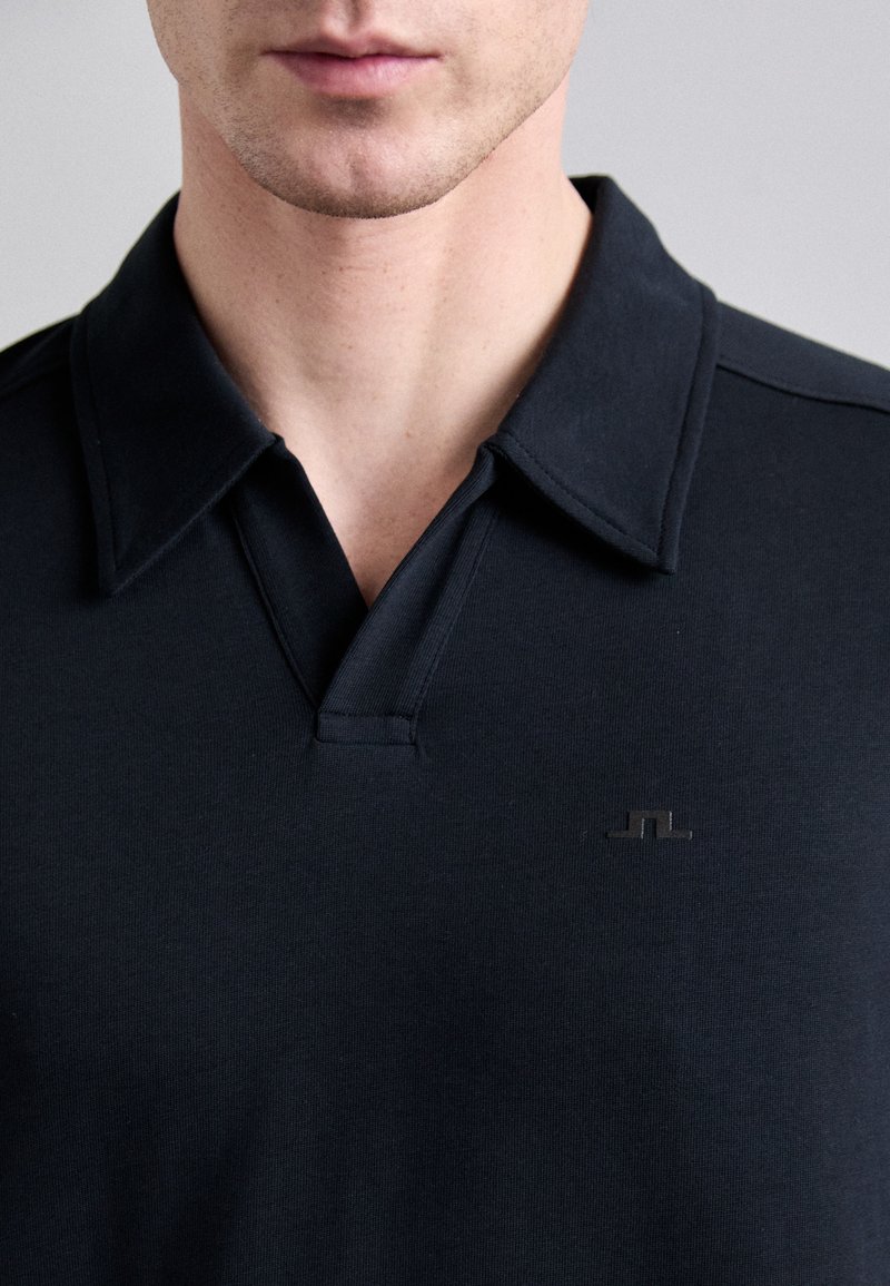 Svart polo skjorta med en solid design, som har en distinkt krage och subtil logotyp. Tillverkad av ett mjukt material, har den en figurnära siluett.
