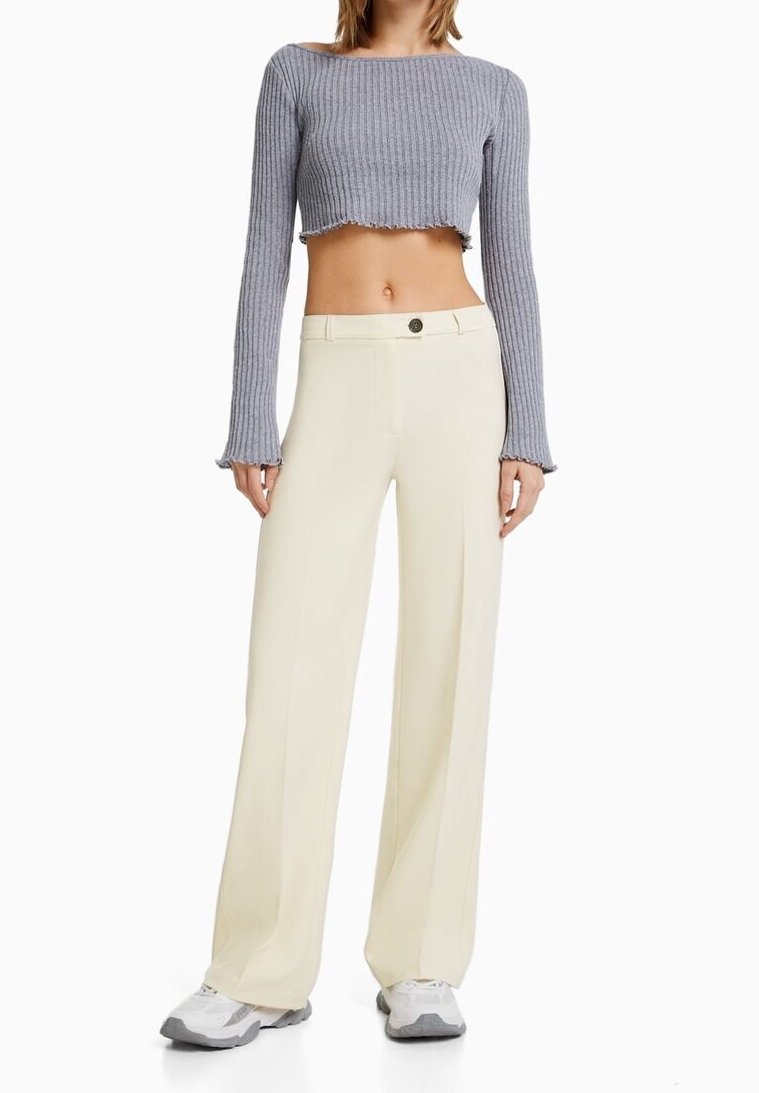 Haut à manches longues cropped côtelé gris associé à un pantalon large crème doté d'une fermeture à bouton, d'une texture lisse et d'un design ajusté.