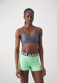 Sujeción gris con tirantes delgados y logo negro de Under Armour; pantalones cortos ajustados en verde menta con cinturilla elástica negra y logo.