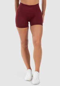 Bordeaux sportieve shorts met een hoge elastische tailleband en een gladde, aansluitende pasvorm. Gekocht met witte sportschoenen.