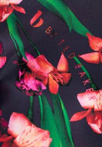 Tela oscura con flores brillantes en tonos rosa y naranja, hojas verdes y texto rojo que dice "BY TED BAKER" debajo de un logotipo estilizado de una "b" roja.