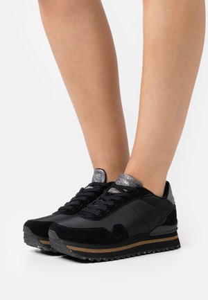 Schwarze Sneaker aus Wildleder und synthetischem Material, mit strukturierten grauen Akzenten, Schnürverschluss und Gummisohle mit gestreiftem Muster.