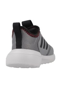 Chaussures de sport en maille grise avec une semelle blanche, dotées d'accents noirs et de surpiqûres rouges. Design à enfiler avec une languette au talon pour un enfilage facile.