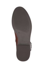 Zapato de cuero marrón con suela de goma texturizada, que presenta un acento de hebilla y un panel superior liso. La suela tiene un patrón de diamante para un mejor agarre.