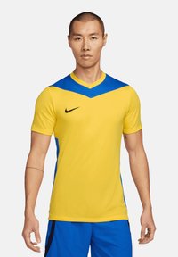 Maglietta Nike con un corpo giallo e un design a yoke blu, maniche corte e scollatura a V. Tessuto liscio e leggero, adatto per lo sport.