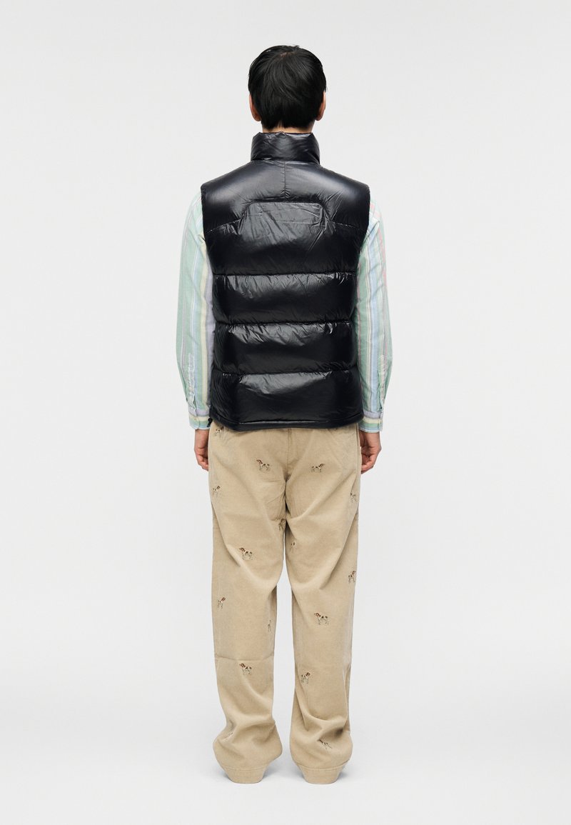 Veste matelassée bleu marine avec col montant et design matelassé, associée à un pantalon en velours côtelé beige orné de petits motifs brodés de chiens.