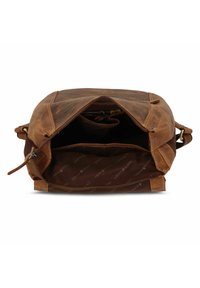 Bruine leren schoudertas openslaand van boven, met een donkere stoffen binnenkant. Kenmerken zijn onder andere een ritssluiting en een extra compartiment.