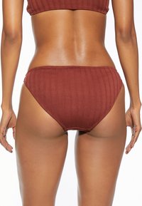 Gerippter Bikiniunterteil in gebranntem Orange, mit niedriger Leibhöhe, glatter Textur und elastischem Bund. Schlichte Naht entlang der Kanten.