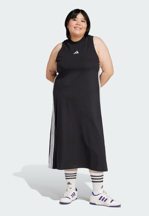 Schwarzes ärmelloses Kleid mit weißen Dreistreifen-Akzenten an den Seiten, aus glattem Stoff gefertigt, kombiniert mit weißen und lila Sport Schuhen sowie gestreiften Socken.