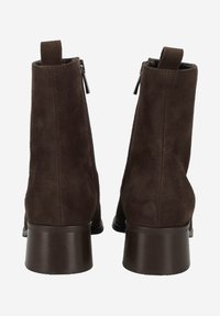 Bottines en suède marron avec une finition lisse, des fermetures éclair sur le côté et un talon épais. Comprend une languette à l'arrière pour un enfilage facile.