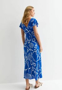 Abito maxi blu con motivi bianchi di frutta e vortici, maniche corte a volant, design a V sulla schiena, realizzato in un tessuto morbido, lungo fino al pavimento.