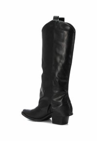Bota de cuero negra hasta la rodilla con un tacón bajo y tiradores en la parte superior, mostrada desde un ángulo lateral sobre un fondo blanco.