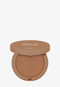Polvo bronceador en un estuche compacto y redondo con una tapa brillante de color marrón claro, con el texto "Wonder Me Shiny Bronzer" y una superficie bronceada lisa.