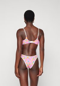 Blumiger Bikini in rosa, orange und gelben Farbtönen, mit weißen Akzenten und verstellbaren Trägern. Glatter Stoff mit einer taillierten Passform.