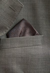 Graue Stoff-Sakkojacke mit einem braun gemusterten Einstecktuch, ordentlich gefaltet in der Brusttasche.