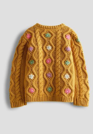 Keltainen neulepusero, jossa on teksturoitu puikkokuvio ja värikkäitä kukka-embroidery koristeita vaaleanpunaisella, sinisellä ja vihreällä sävyllä.