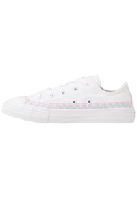 Baskets en toile blanche avec un motif zigzag multicolore sur les côtés, embout en caoutchouc et semelle blanche. Six œillets pour les lacets.