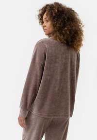 Bruine, zachte velours top met lange mouwen, een relaxte pasvorm, ronde halslijn en minimale stikdetails. Heeft verlengde mouwen en een comfortabel ontwerp.