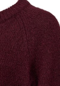 Burgundy stickad tr�öja med ett texturerat tyg, rund halsringning och raglanärmar, som visar en mjuk och fluffig utseende.