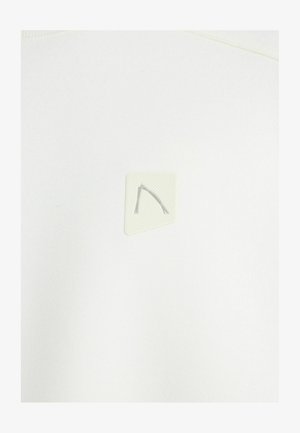 Valkoinen collegepaita, jossa on teksturoitu kolmionmuotoinen paikka, jossa on hienovarainen kohokuvioitu kuvio ja vaaleanharmaat korostusviivat.