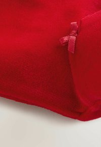 Tessuto in pile rosso con una consistenza morbida, con un piccolo dettaglio in nastro rosa nell'angolo. La forma è rettangolare, con bordi lisci.