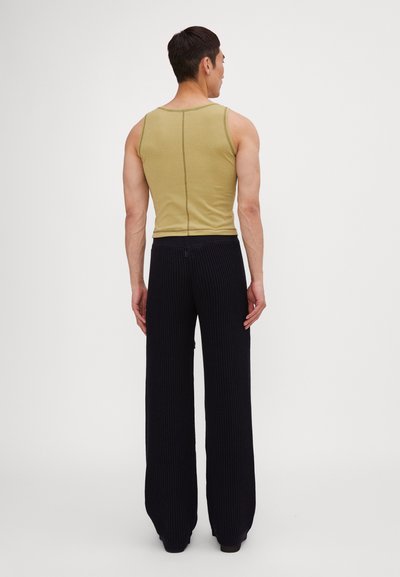 Top de tip slim-fit, de culoare verde măslin, cu decolteu rotund și cusătură pe spate, asortat cu pantaloni largi, texturați, de culoare albastră marin, cu un model subtil.