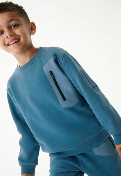 Felpa blu con finitura testurizzata, caratterizzata da una tasca con zip sul petto e dettagli blu coordinati sul braccio. Tessuto morbido, design casual.