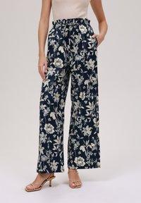 Blomstrede vide bukser i marineblå, lavet af letvægtsstof med en flæse i livet, med cremefarvede blomster mønstre og sidelommer.