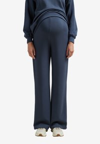 Navyblaue Sweatpants im entspannten Schnitt mit weitem Bein, gefertigt aus weichem Stoff, mit glatter Textur und elastischem Bund.