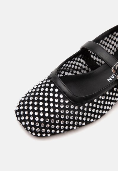 Chaussure Mary Jane noire avec une bride, couverte de petits strass argentés espacés régulièrement et d'un motif en résille à l'intérieur.