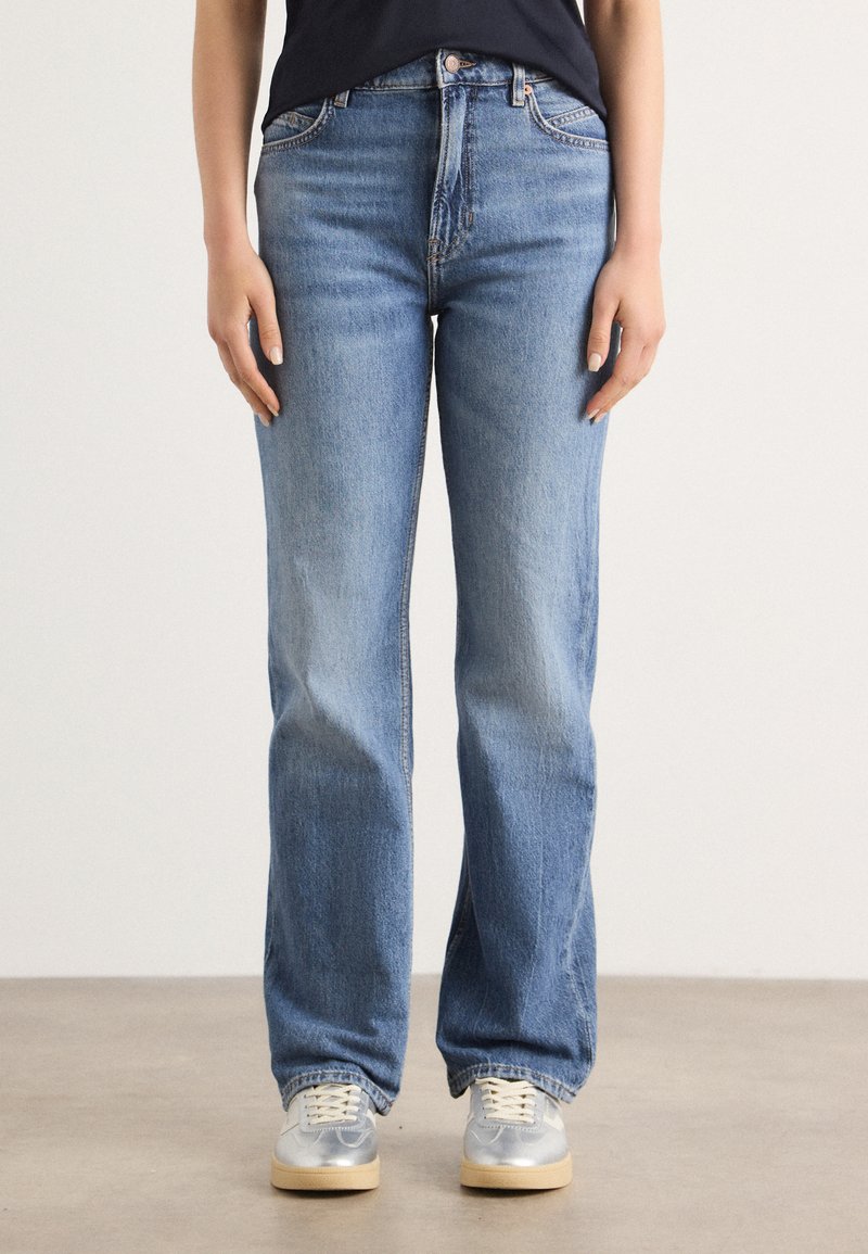 Lichtblauwe, rechte jeans gemaakt van denim. Bevat vijf zakken, knoopsluiting en subtiele vervaging. Gecombineerd met zilveren sneakers.