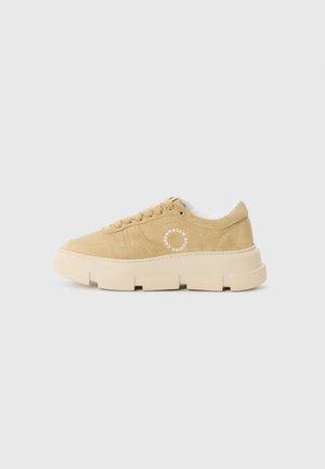 Sneaker in camoscio beige con suola spessa color crema, punta rotonda, piatto rialzato e dettaglio del logo bianco sul lato. Lacci e colletto imbottito.