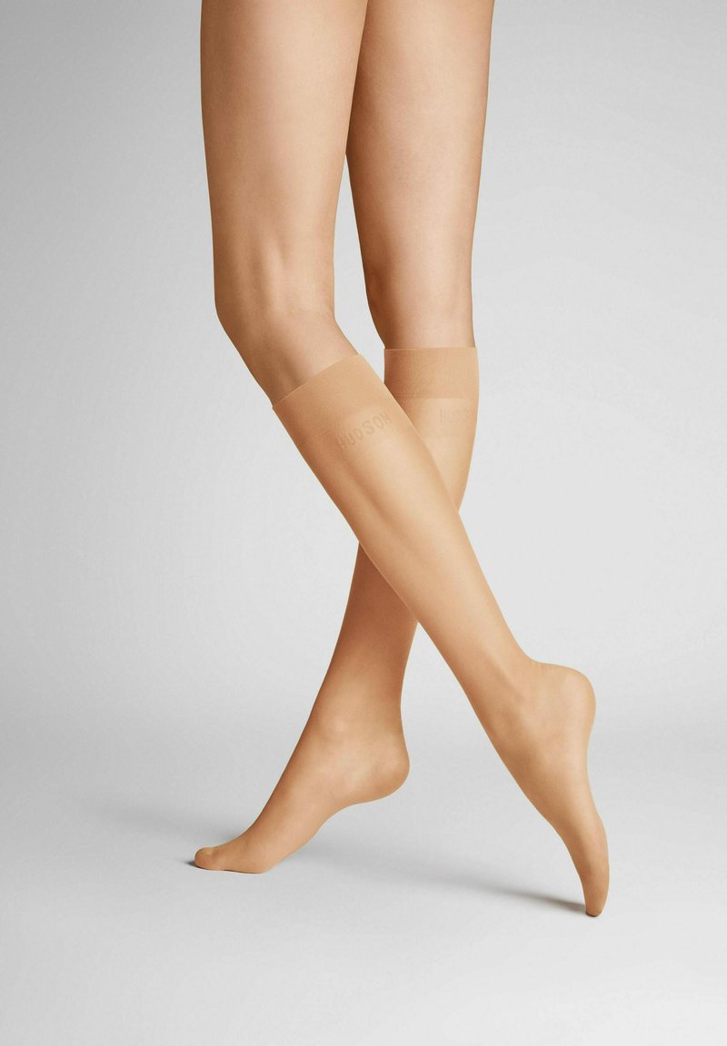 Nudefarbene knielange Strümpfe mit einer glatten, transparenten Oberfläche, versehen mit einem Bund an der Oberseite und subtiler Markierung an der Seite.