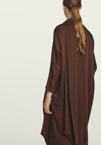 Bruin, lang mouwend kledingstuk met een vloeiende ontwerpen en zachte textuur, die vanuit de rug naar beneden valt met een subtiele glans.