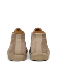 Beige Wildleder-High-Top-Sneaker mit glatter Textur, elastischen Seitenpaneelen, einem hellbraunen Innenfutter und einer cremefarbenen Gummisohle.