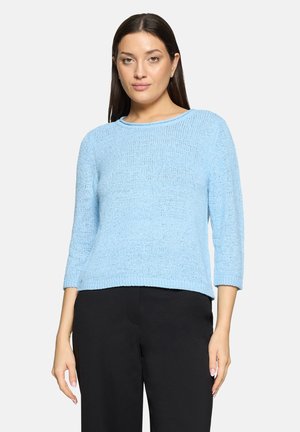 Pull tricoté bleu clair avec manches trois-quarts, col rond et coupe décontractée, associé à un pantalon noir.