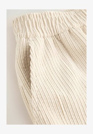Jasno-kremowa tkanina sztruksowa z wyraźną pionową teksturą prążków; posiada elastyczny pas dla elastyczności i komfortu.