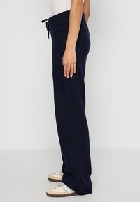 Marineblauwe geweven sweatpants met een geribbelde tailleband, zijzakken en een verstelbaar trekkoord, voorzien van een relaxte, rechtvallende pasvorm.