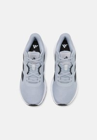 Light gray athletic shoes with black accents, mesh upper, and flat laces; featuring a padded collar and textured sole for traction.