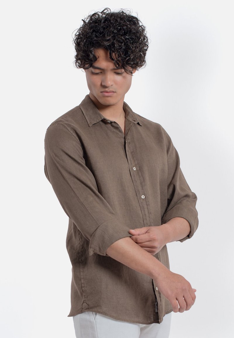 Camicia marrone a maniche lunghe realizzata in tessuto leggero, con colletto a bottoni, taschino sul petto e maniche arrotolate.