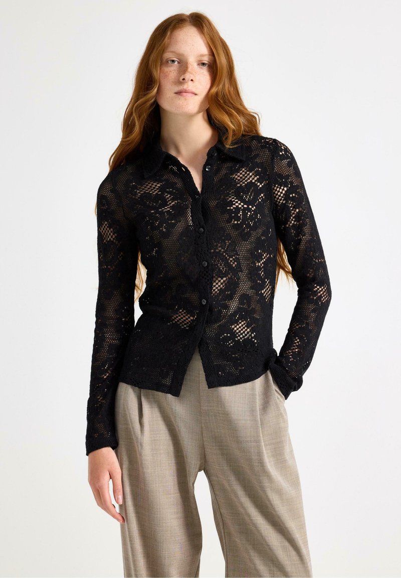 Svart spets skjorta med knappar, blommönster, långa ärmar och krage. Kombinerad med ljusbeige skräddarsydda byxor.