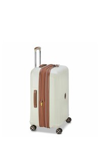 Valise rigide crème avec accents marron, double zips, poignée télescopique, et quatre roulettes pivotantes pour la mobilité. Sides texturés pour une prise en main.