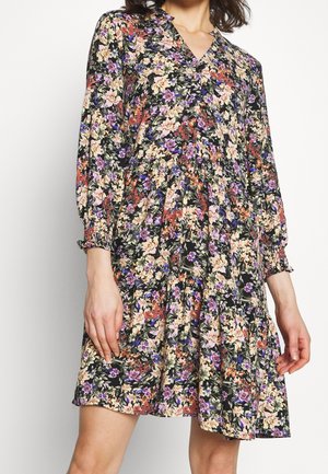 Bloemenjurk met een zwarte achtergrond en roze, paarse en oranje bloemen. Lange mouwen met geplooide manchetten en een V-hals.