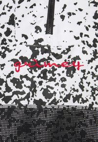 White and black speckled fabric with a black zipper and red embroidered "grainey" text above black mesh material.