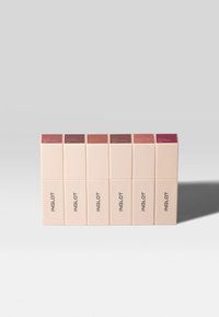 Six boîtes de couleur crème avec des dessus carrés, comportant des étiquettes de différentes nuances de mauve et de rose, affichant les noms des produits et la marque "INGLOT."